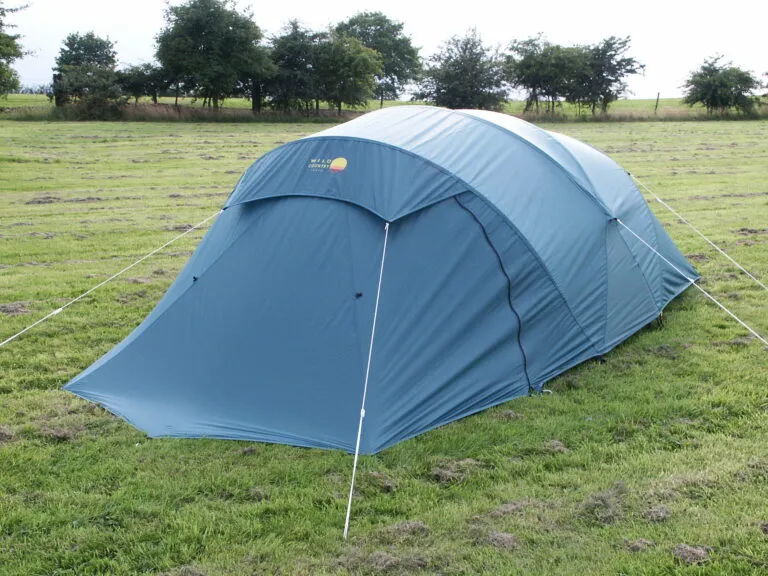 Blue camping tent set up on a grassy field, surrounded by trees, ideal for outdoor adventures and family camping trips.