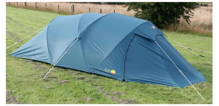 Blue camping tent set up on green grass, showcasing its spacious design and sturdy structure, ideal for outdoor adventures and family camping trips.
