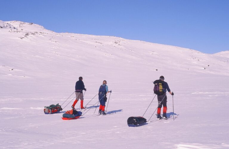3 explorers pulling their pulk sleds in a snow covered landscape