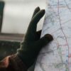 Person holding a map with a gloved hand, indicating navigation or travel planning.