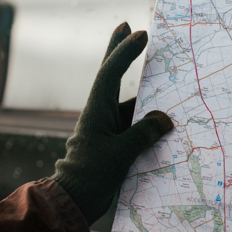 Person holding a map with a gloved hand, indicating navigation or travel planning.