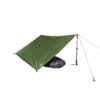 Green tarp pitched as a lean-to over a purple sleeping bag, supported by an adjustable trekking pole and tied-off guy lines on a white background