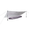 Silver emergency tarp pitched as a low shelter using two adjustable trekking poles and guylines, covering a purple mummy-style sleeping bag beneath.