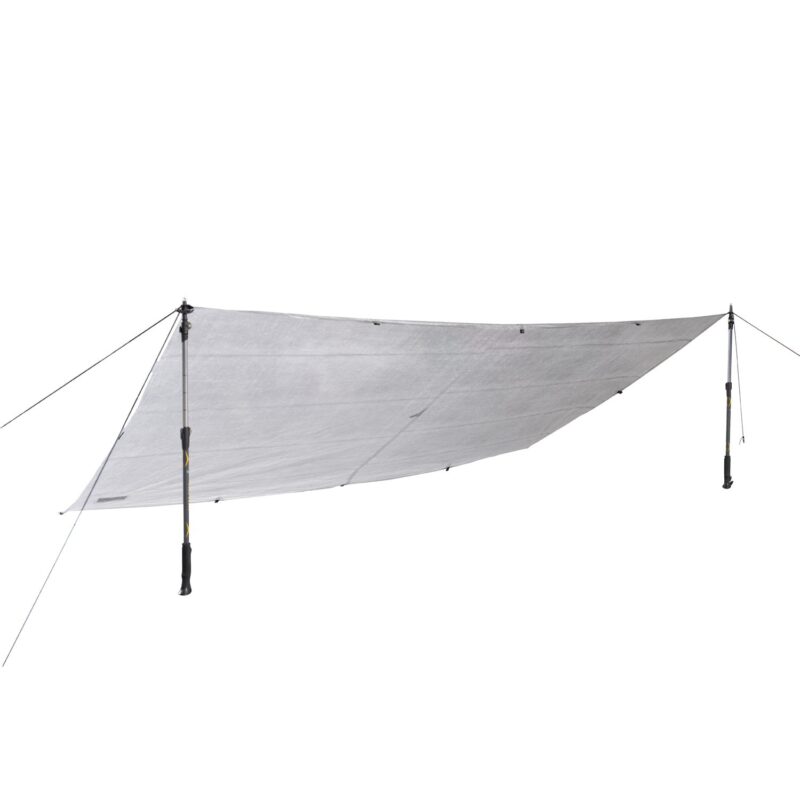 Light grey rectangular camping tarp stretched into a low angled shelter, tensioned by two adjustable trekking poles with guy lines and stake points against a white background.