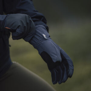 Close-up of a person wearing high-performance outdoor gloves, adjusting the cuff. The gloves feature a durable, weather-resistant design suitable for various outdoor activities.