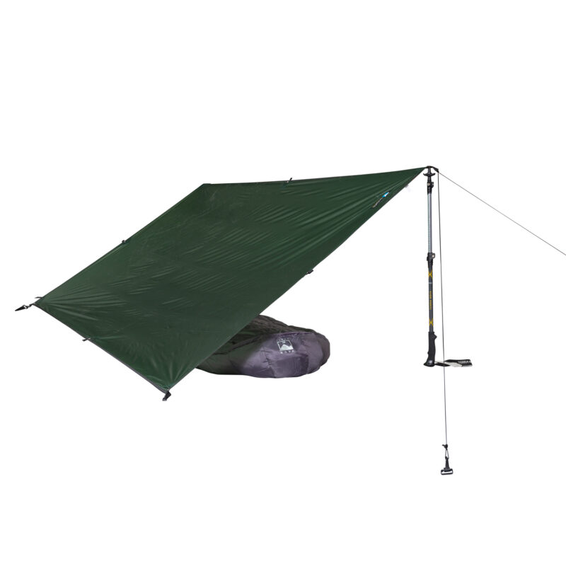 Green rectangular camping tarp pitched as a slanted shelter on a trekking pole with guy lines, a grey sleeping bag partially visible underneath, on a white background.
