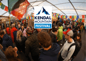 Crowd of attendees at the Kendal Mountain Festival, showcasing vibrant stalls and decorations under a large tent, promoting outdoor activities and adventure culture.