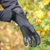 Black gardening gloves being worn by a person, with colorful foliage in the background, showcasing durability and grip for outdoor tasks.