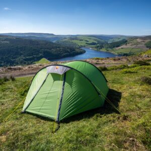 Bright green dome tent pitched on a grassy hillside overlooking a winding reservoir, wooded slopes and patchwork green hills beneath a clear blue sky.