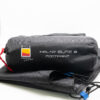 Black cylindrical storage bag marked "WILD COUNTRY" and "HALNY ELITE 2 FOOTPRINT", cinched with a red cord and resting on folded black tent fabric.