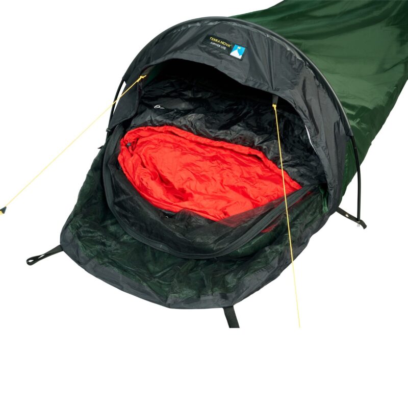 Green single-person bivvy-style tent with a black hood and yellow guy lines, its entrance open to reveal a bright red sleeping bag inside