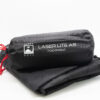 Black Terra Nova Laser Lite A5 footprint rolled in a cylindrical stuff sack with white logo and red drawcord, resting on folded black fabric.