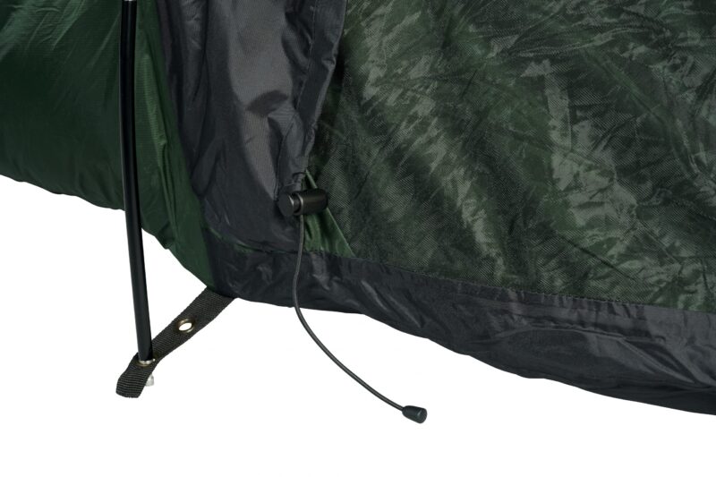 Close-up of a green and black tent base showing a black support pole through a stitched fabric strap with a metal grommet and a loose drawcord ending in a plastic toggle.