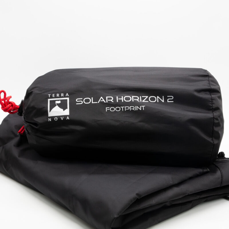 Black cylindrical stuff sack with a white mountain-flag logo and the text 'TERRA NOVA SOLAR HORIZON 2 FOOTPRINT', featuring a red drawcord and resting on folded black fabric against a white background.