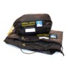 Black Terra Nova Equipment stuff sack with yellow logo patch and small mountain icon sitting on a folded black waterproof sheet showing brass grommets and a knotted drawcord