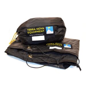 Black Terra Nova Equipment stuff sack with yellow logo patch and small mountain icon sitting on a folded black waterproof sheet showing brass grommets and a knotted drawcord