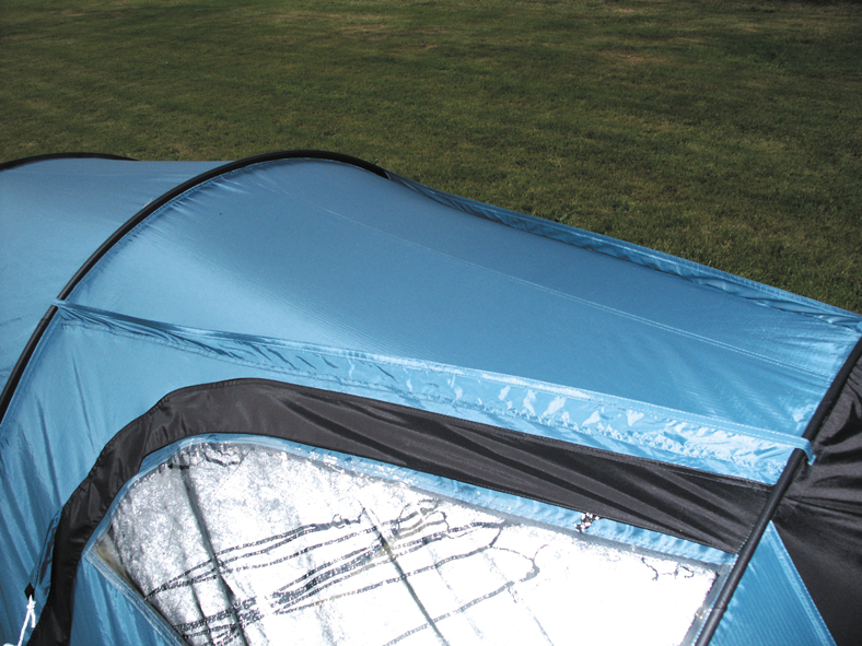 Blue tunnel tent section on a grassy lawn showing curved black poles, waterproof blue fabric and a zippered window with reflective silver inner lining and black trim.