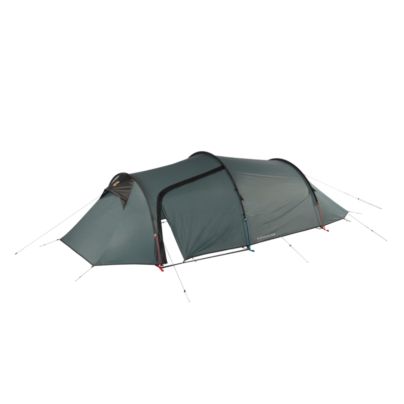 Long dark green tunnel-style camping tent with an extended triangular porch at the front, an arched central entrance flap partly open, black pole seams and multiple guy lines pegged out along the sides