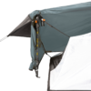 Close-up of a grey-blue tent awning secured by an adjustable trekking pole and orange strap clips, with a white tent wall and taut guy lines visible.
