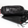 Compressed black stuff sack labelled 'Terra Nova PIONEER LITE 2 FOOTPRINT' with a red drawcord, resting beside folded black groundsheet fabric on a white background.